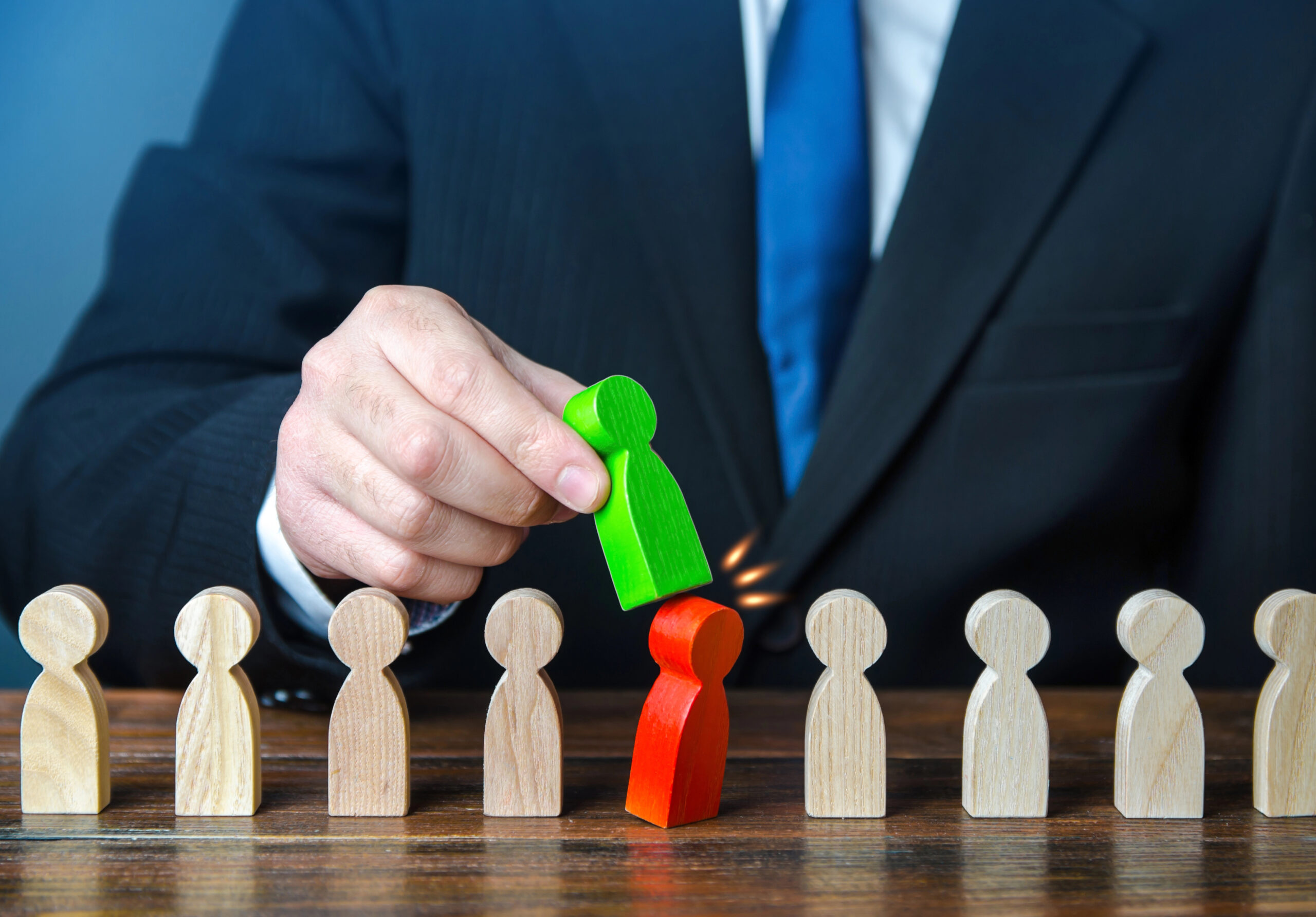 A man in a suit replaces a wooden person symbolizing the high turnover in IT.
