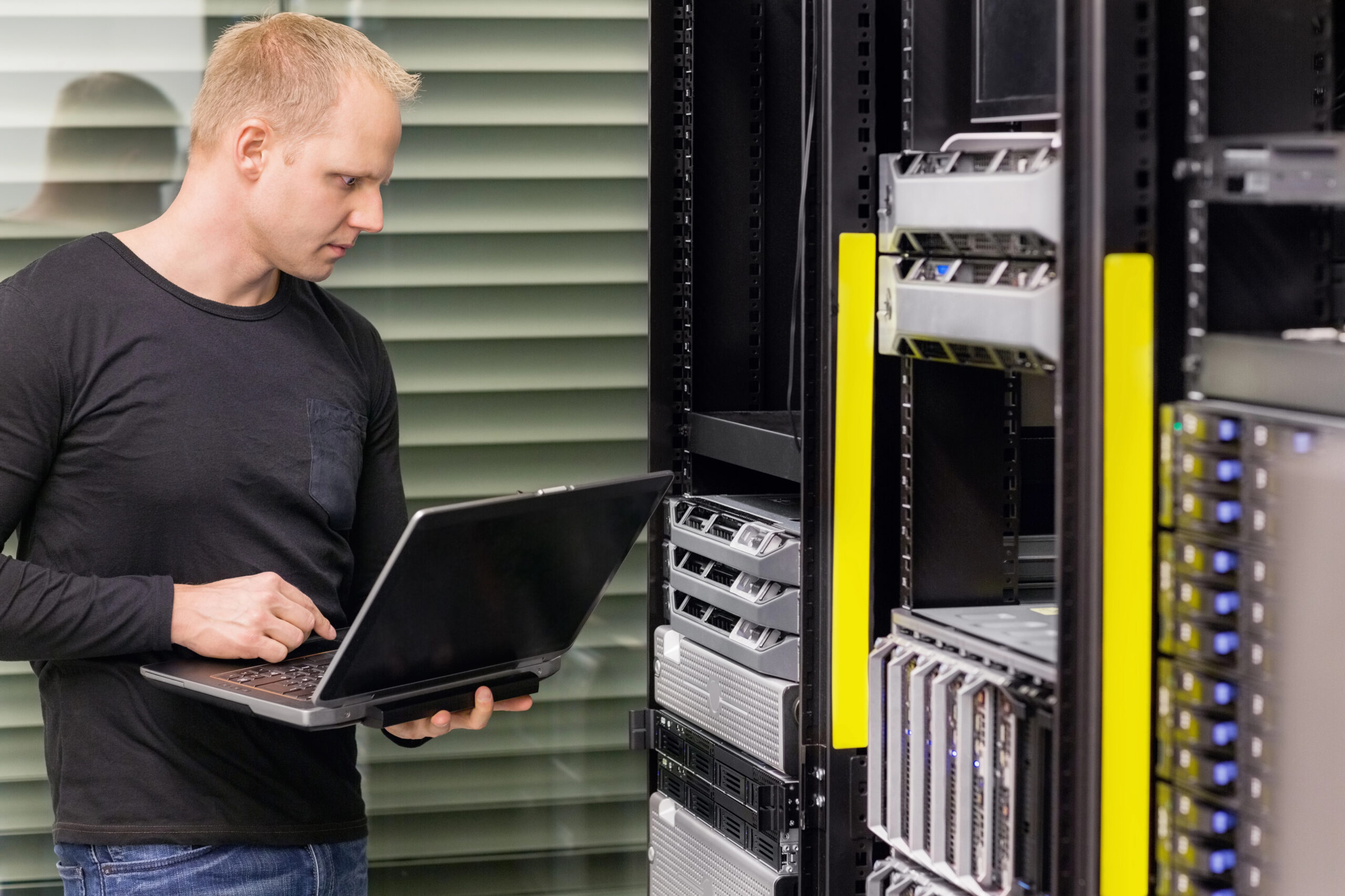 IT consultant evaluates outdated server rack at a manufacturing facility before managed IT service upgrade begins